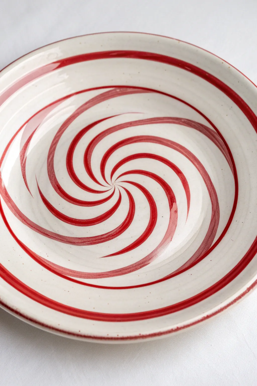Crisp red and white candy cane spiral plate with glossy finish in clean Nordic holiday style