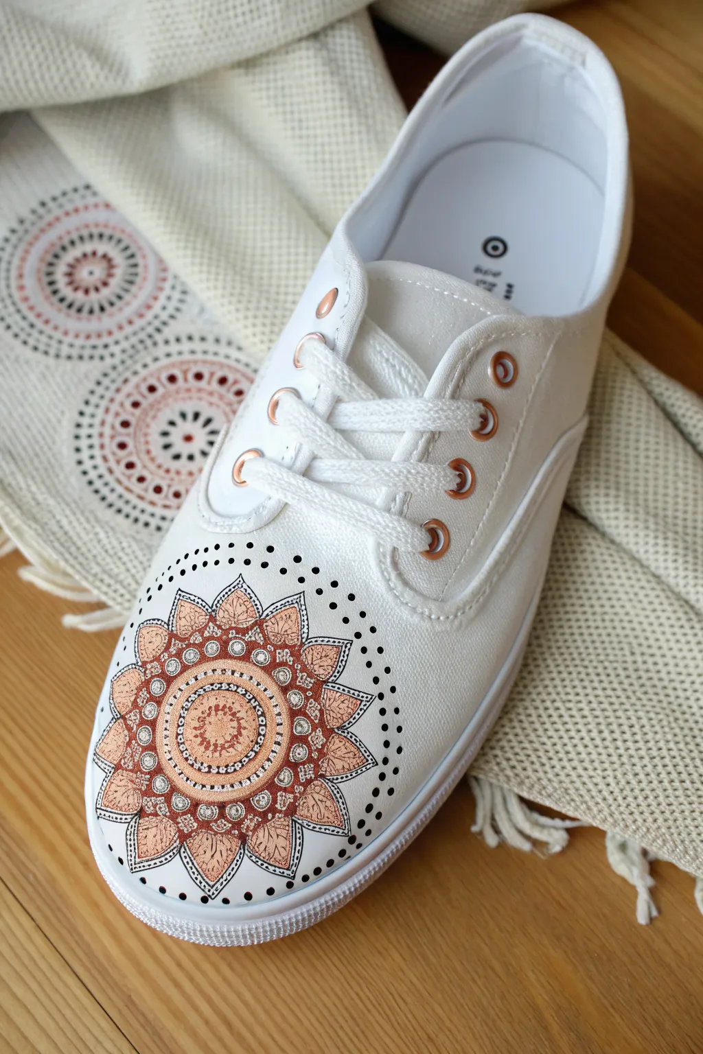 Centered dot-painted mandala medallion on a sneaker toe box with markers and compass nearby