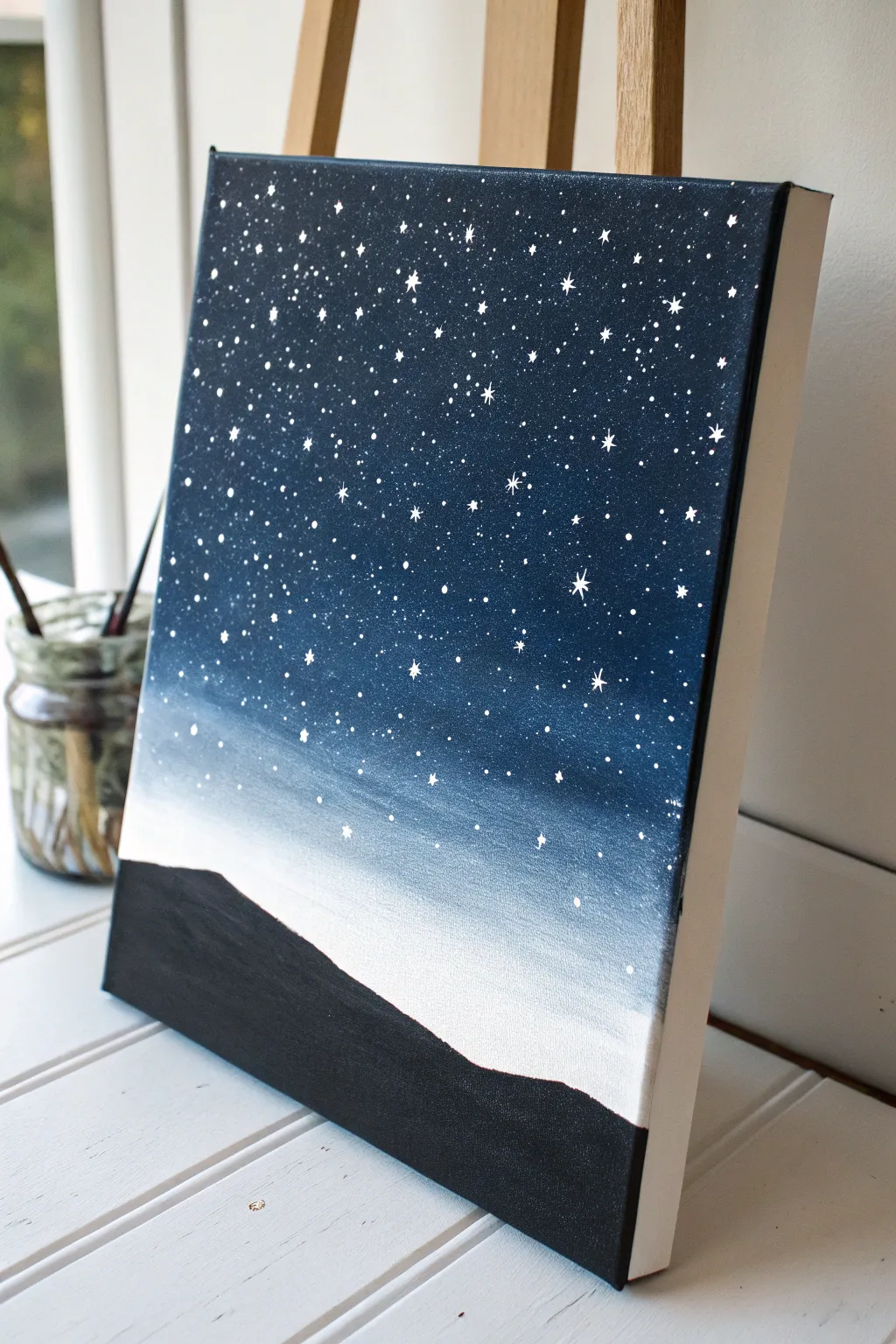 Try a minimalist starry night acrylic: navy wash, splatter stars, and a tiny hill silhouette.
