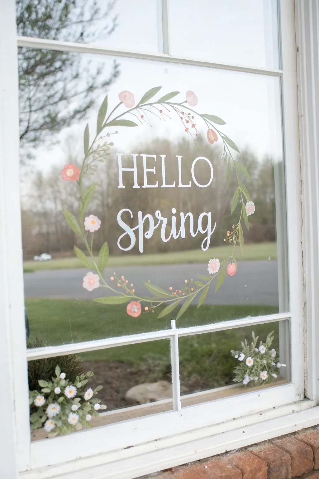 Minimalist spring window art: Hello Spring lettering framed by delicate leaves and blossoms.