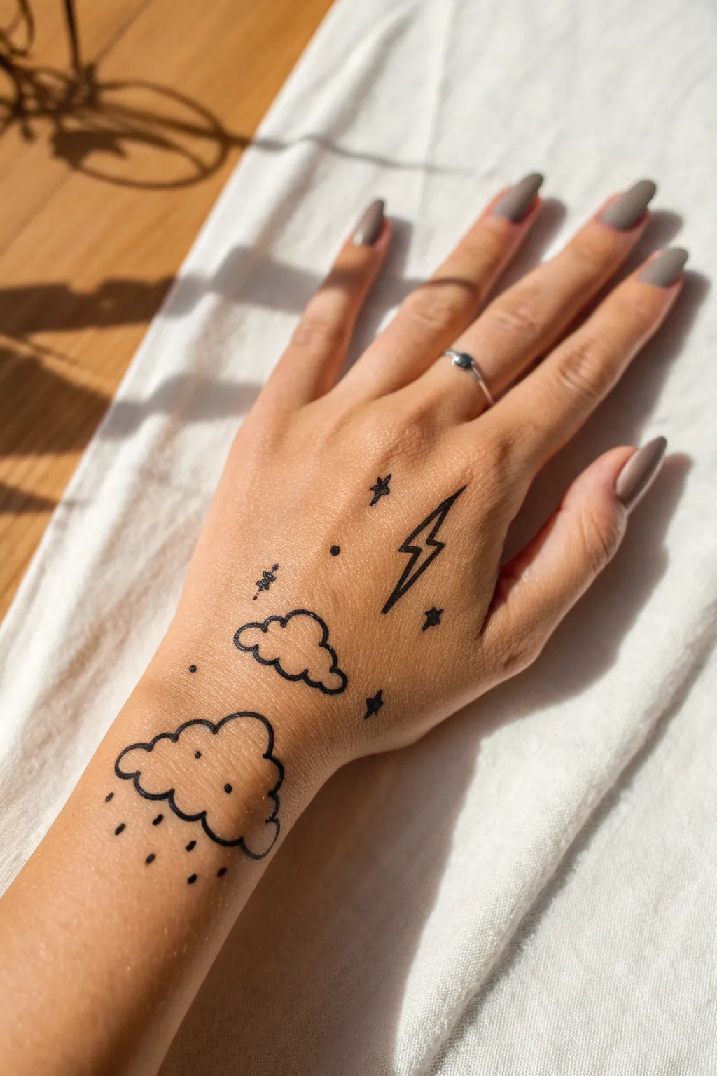 Soft cloud puffs and tiny lightning bolts doodled on fingers, minimal and playful.