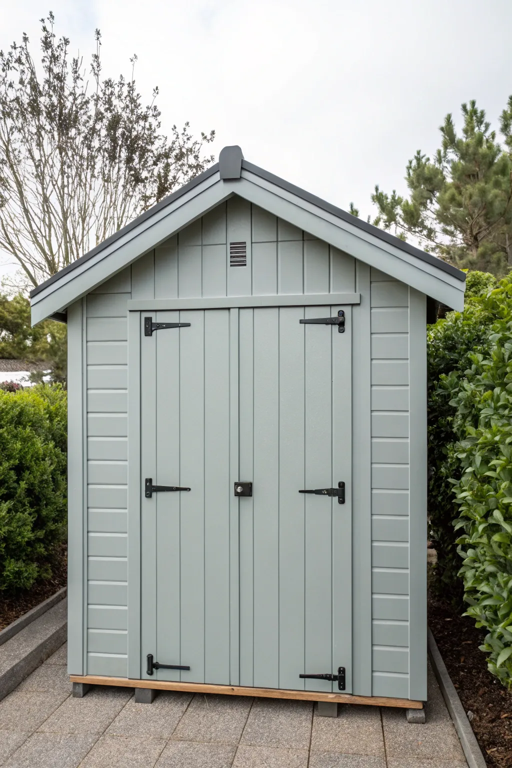 Soft gray shed framed by lush greenery for a calm modern-neutral backyard statement piece.