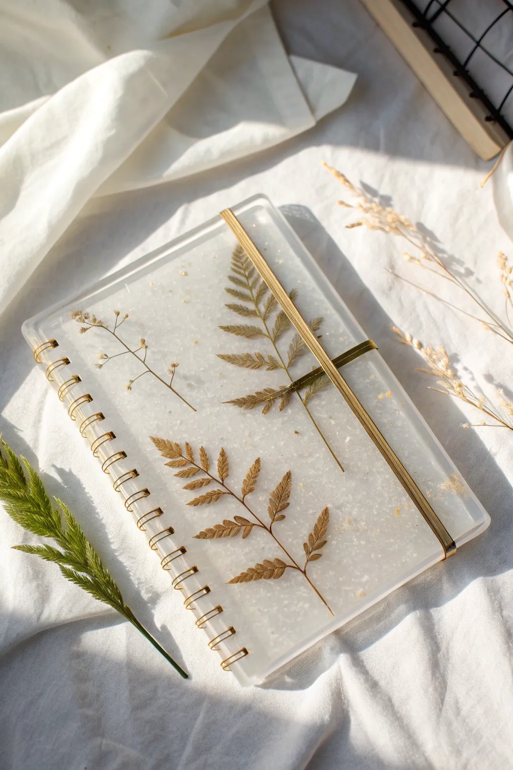 Minimal gold leaf clusters on crystal-clear resin cover, clean white backdrop, airy and elegant.