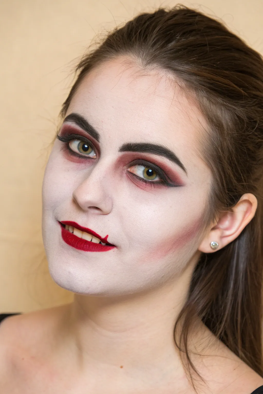 Easy vampire face paint: pale skin, sharp brows, fangs, and a single blood drip lip