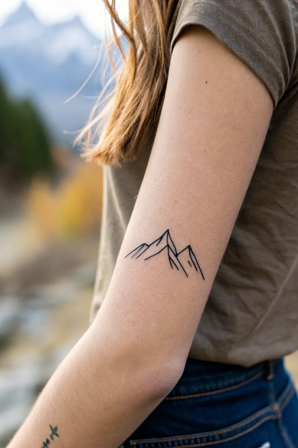 Tiny mountain horizon tattoo in clean linework, lots of negative space, minimalist boho mood