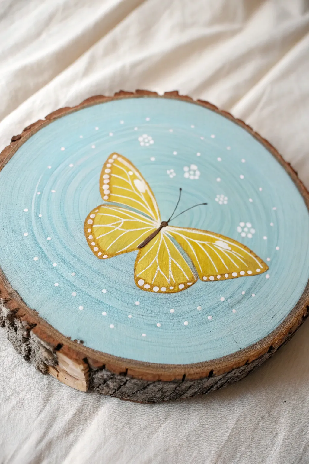 Sky blue wood slice with a bright yellow butterfly, simple, airy, and beautifully handmade