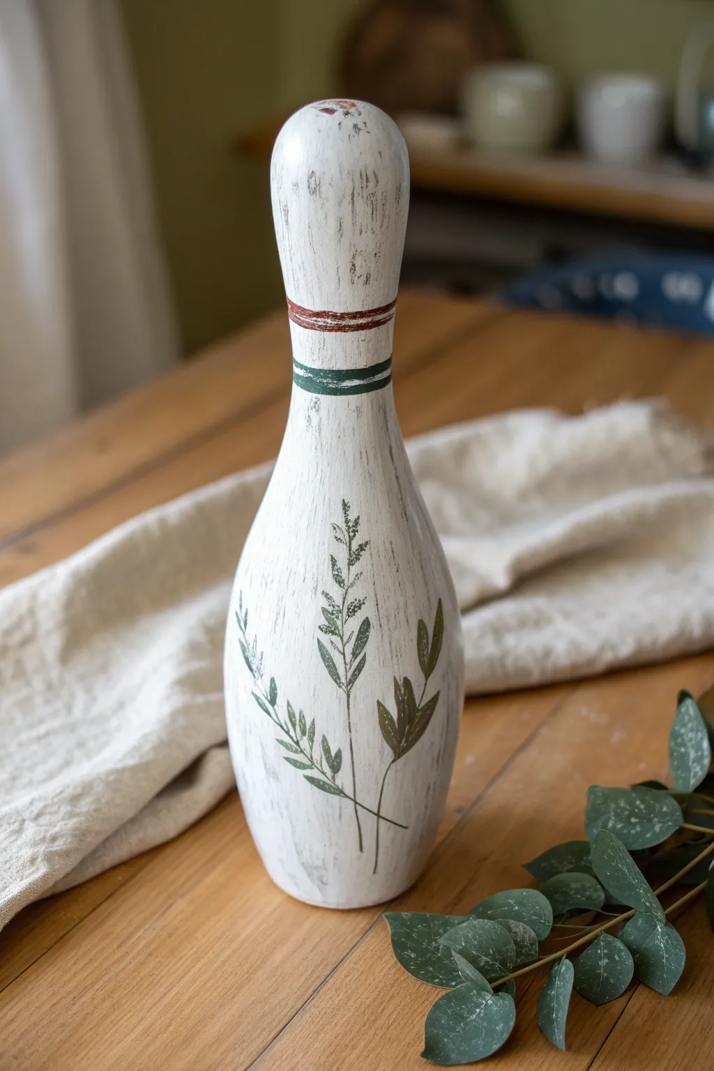 Rustic whitewashed bowling pin with soft eucalyptus sprigs for minimalist boho charm.