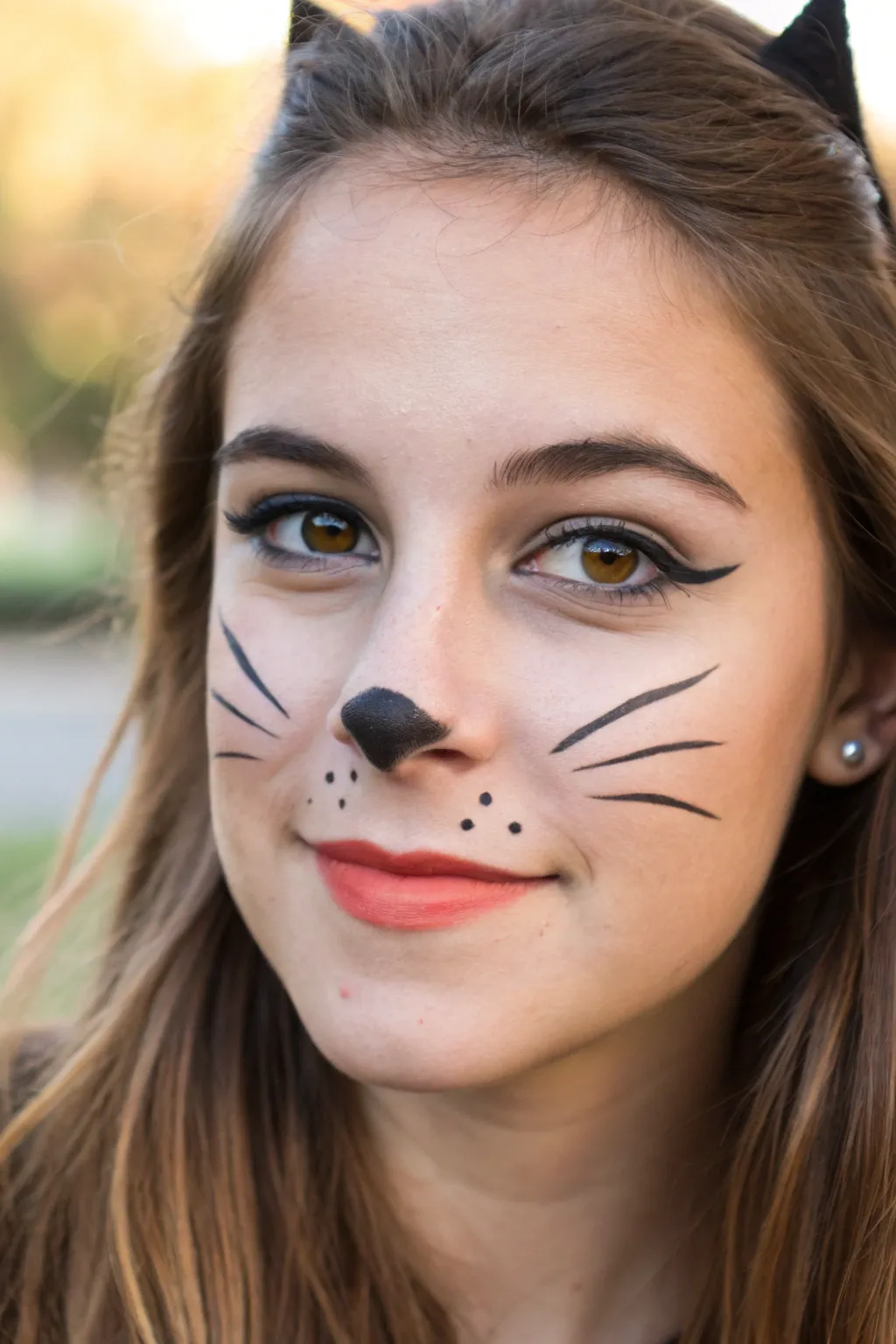 Sweet fall festival face paint: cute black cat whiskers with smoky eyes and warm orange accents