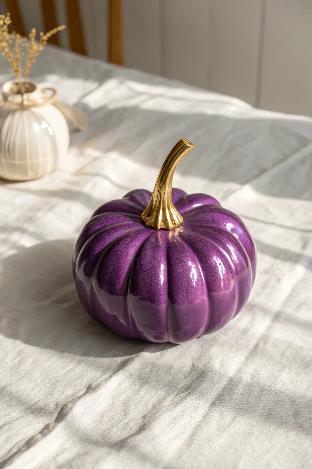 Glossy purple pumpkin with a metallic gold stem for chic minimalist fall decor inspo.