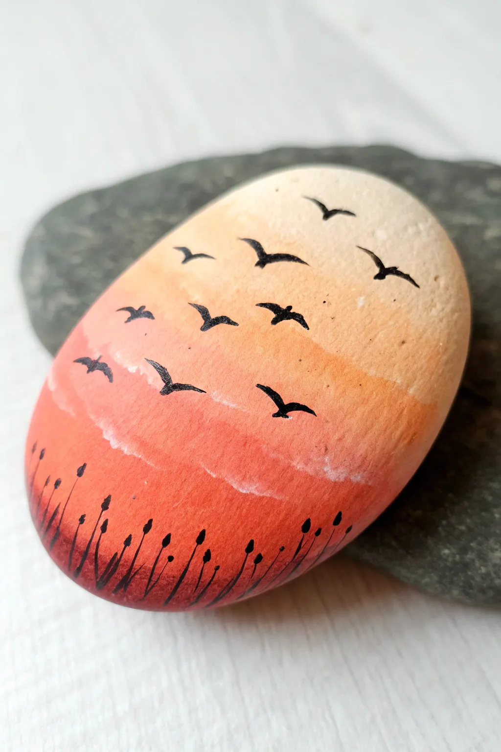 Minimal sunset rock painting with tiny birds in flight, warm gradient glow and crisp contrast