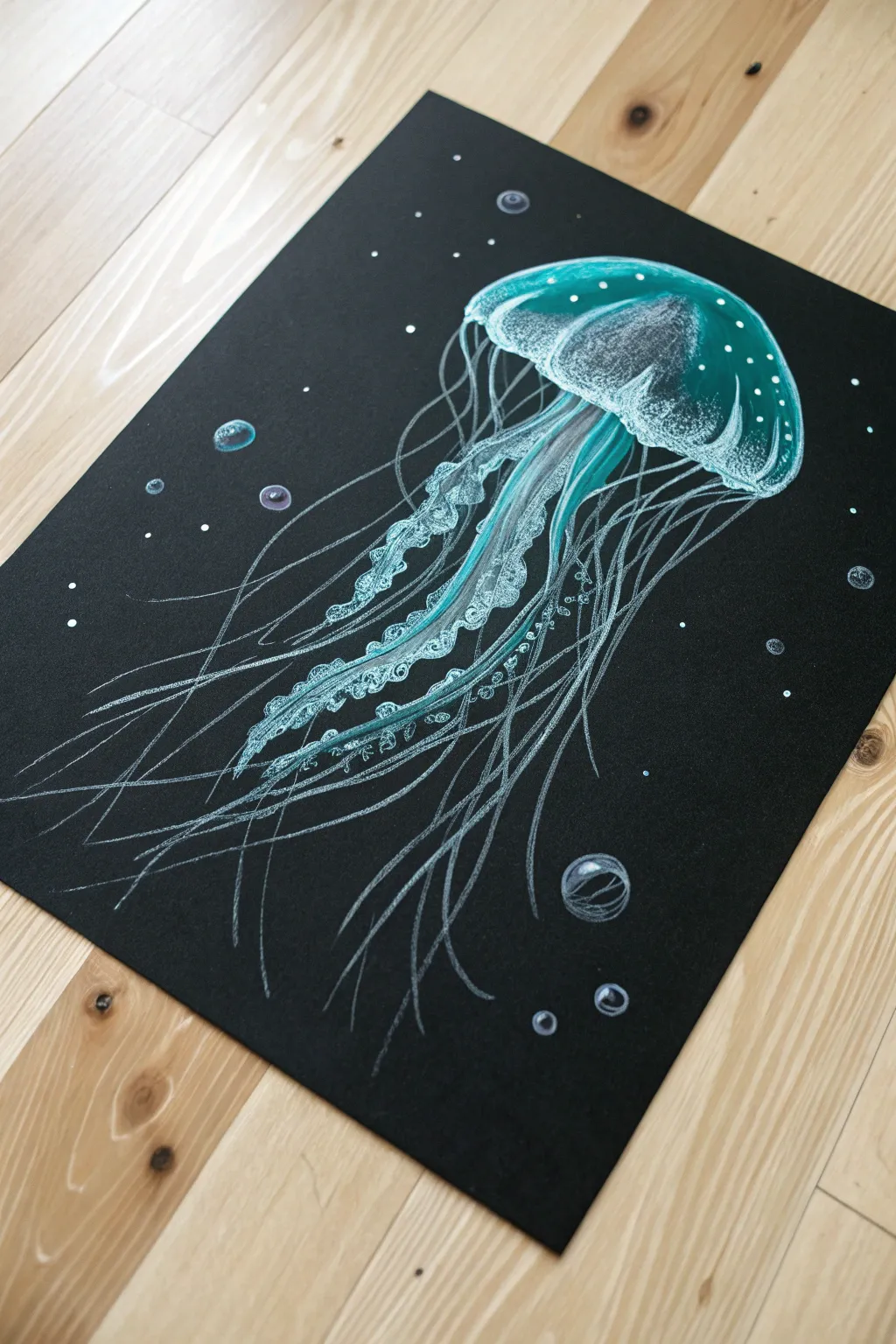 Glowing jellyfish scratch art with wispy bioluminescent lines on deep black paper.