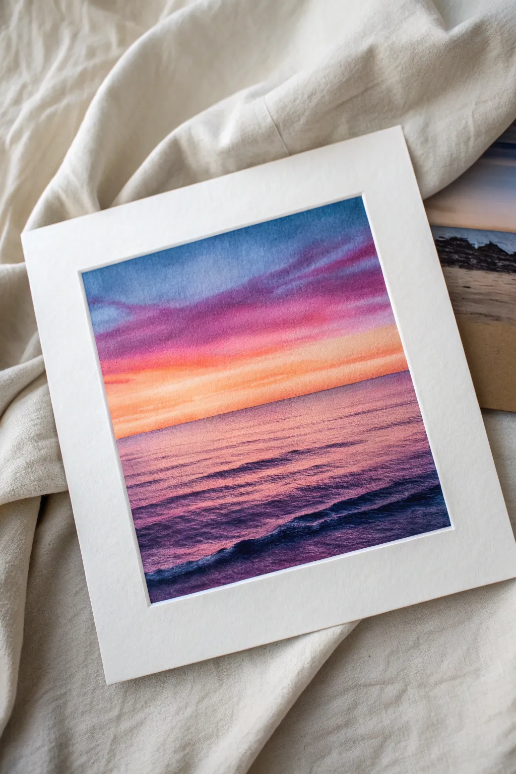 Bold sunset sky bands mirrored on calm ocean water, clean horizon and vast open sky.