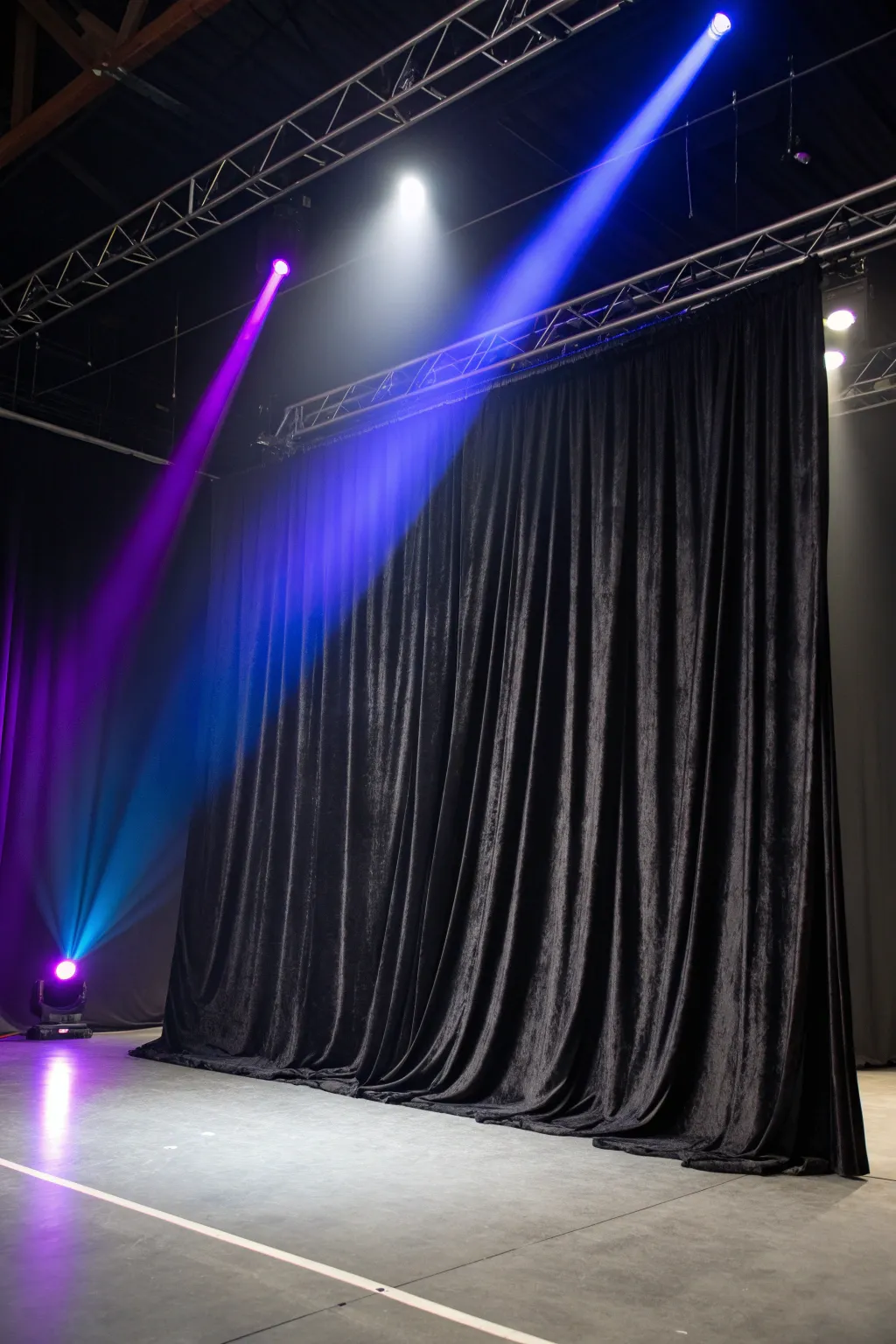 Minimal black drape backdrop with dramatic blue, purple and white beams through haze.