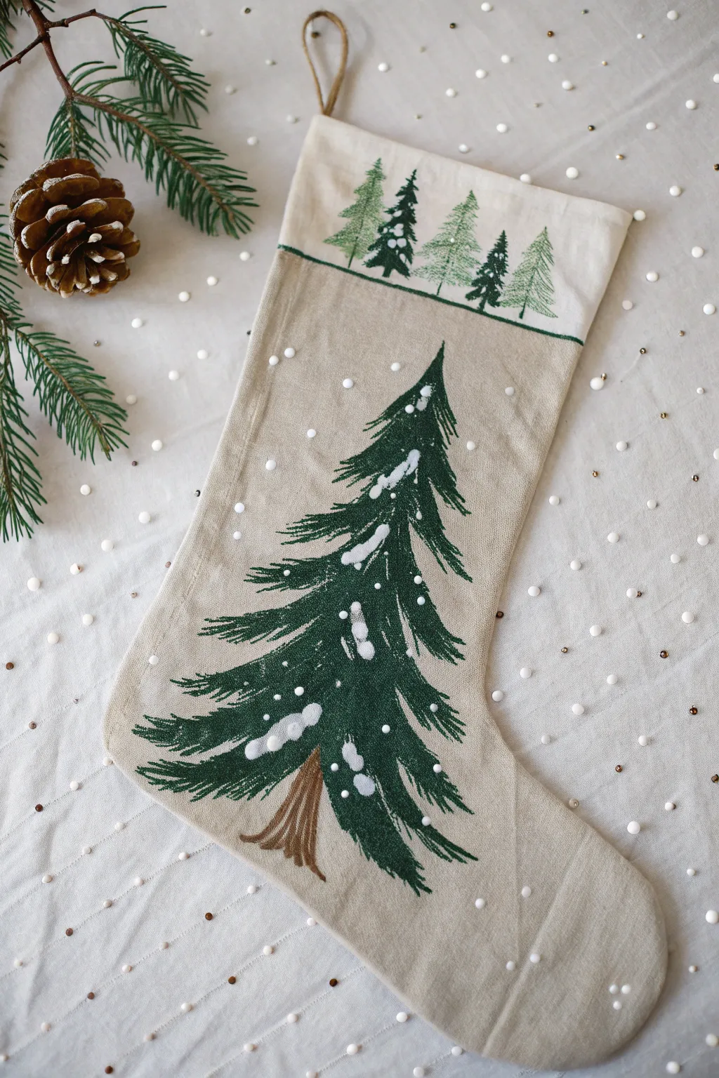 Neutral stocking with a single evergreen tree and snow-tipped branches, minimal and cozy