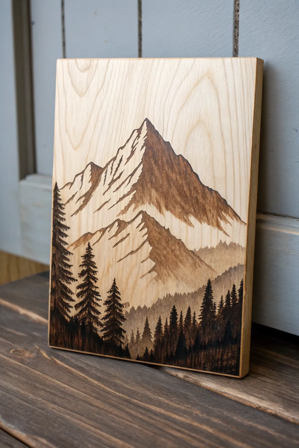 Minimalist pyrography mountain silhouette on warm wood, high contrast with airy negative space