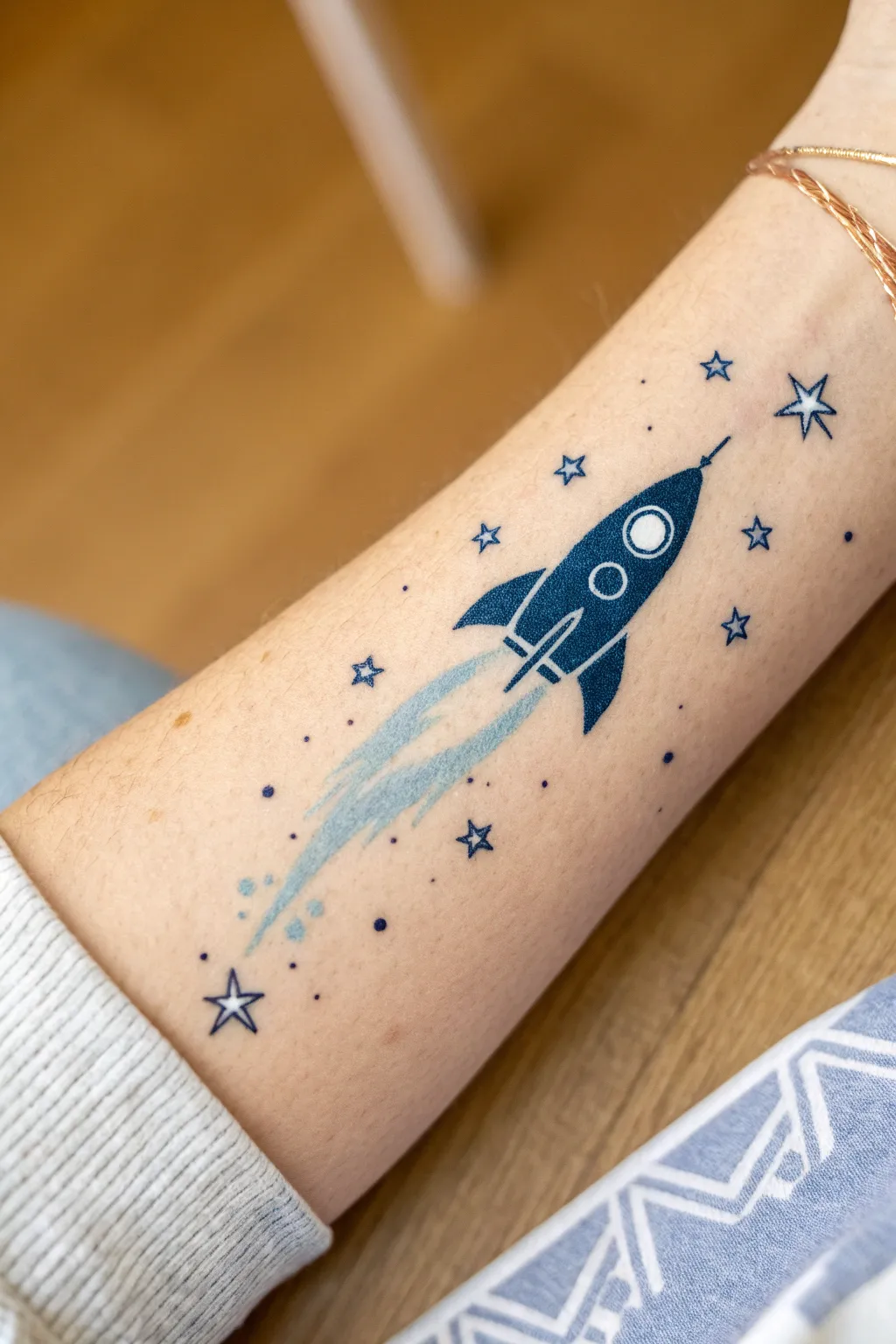 Easy arm painting idea: a tiny wrist rocket with a dreamy star-dot trail in blues and white.