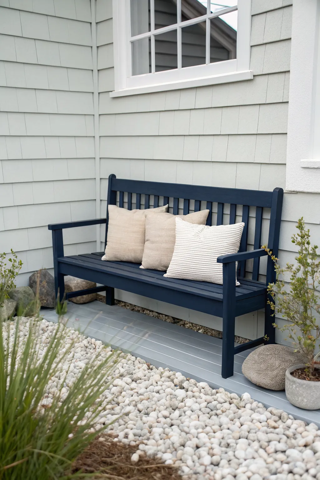 Navy bench with light cushions against pale siding for an effortless coastal calm contrast