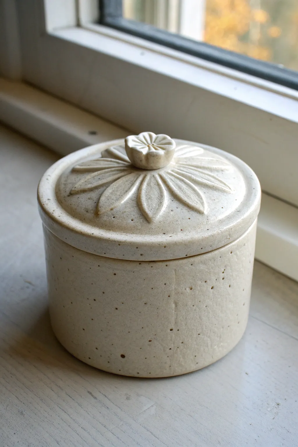 Minimal ceramic box with a floral lid topper, carved petals highlighted by soft shadow contrast