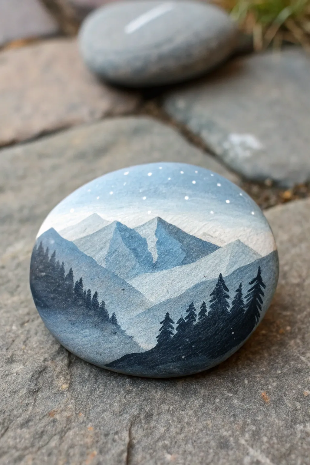 Paint a tiny misty mountain vista inside a perfect circle frame on a smooth river rock.