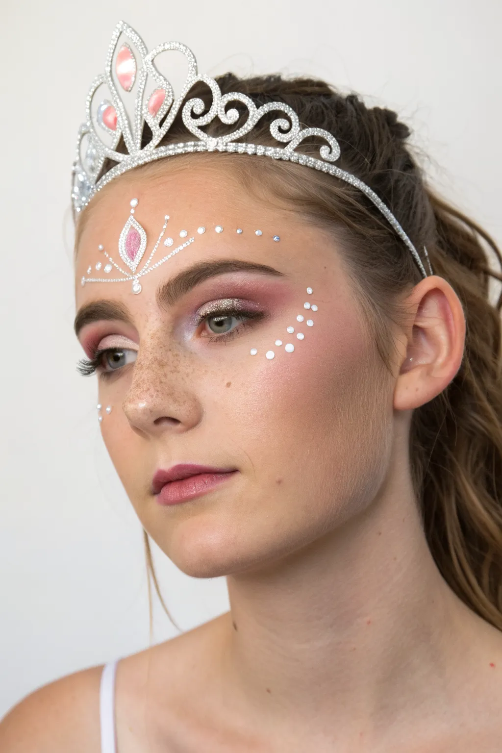 Soft princess tiara face paint with elegant swirls and teardrops, perfect for parties