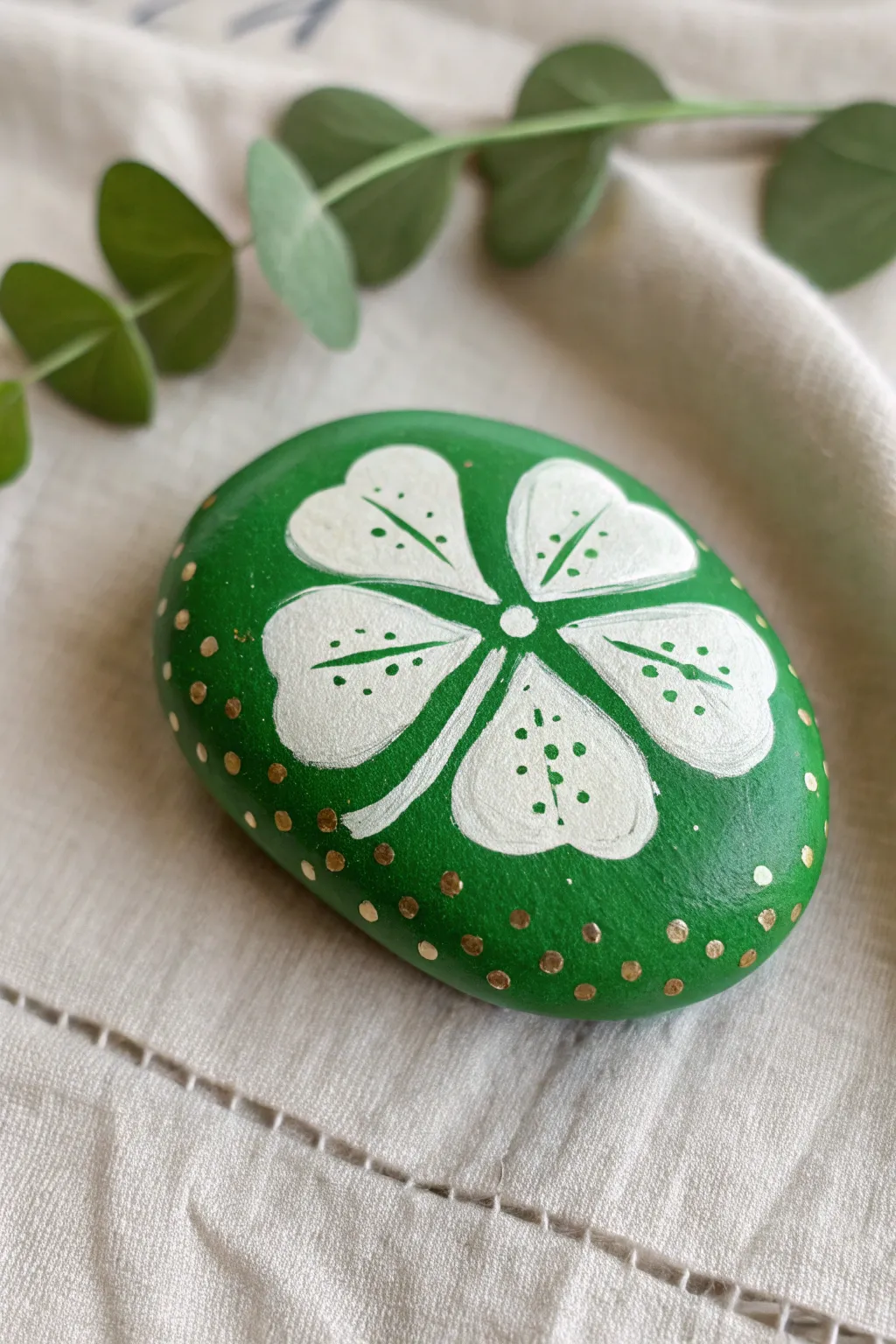 Vibrant green shamrock luck stone with minimalist dots and metallic accents on soft linen