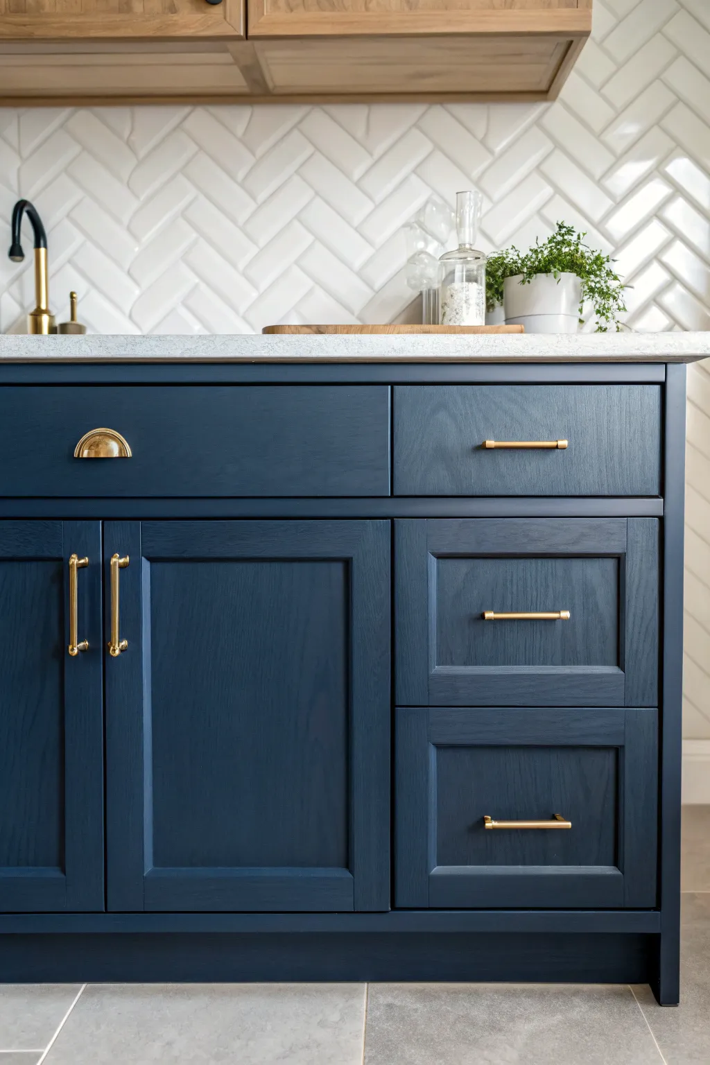 Navy cabinet paint with warm brass pulls, balanced by bright stone and creamy tile.