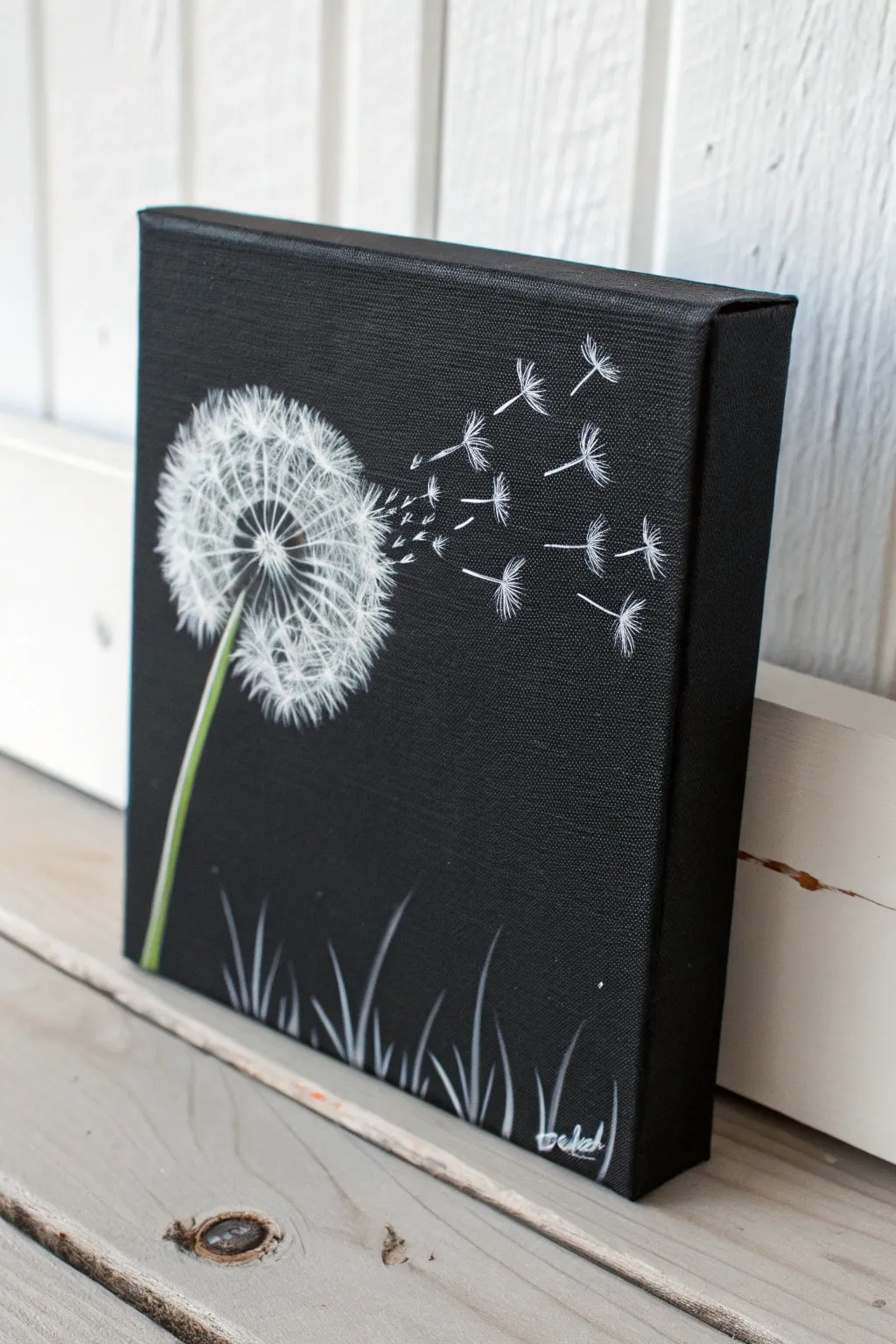 Mini black canvas dandelion puff with drifting seeds, crisp white on deep matte black.