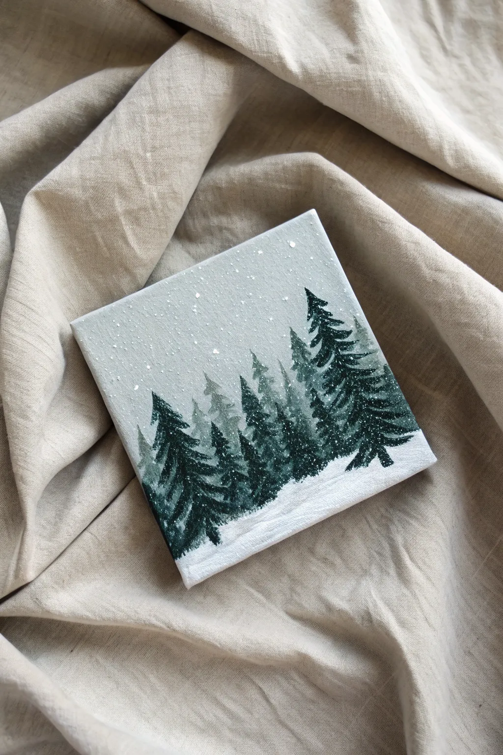 Capture the serenity of winter with this minimalist snowy tree line painting idea.