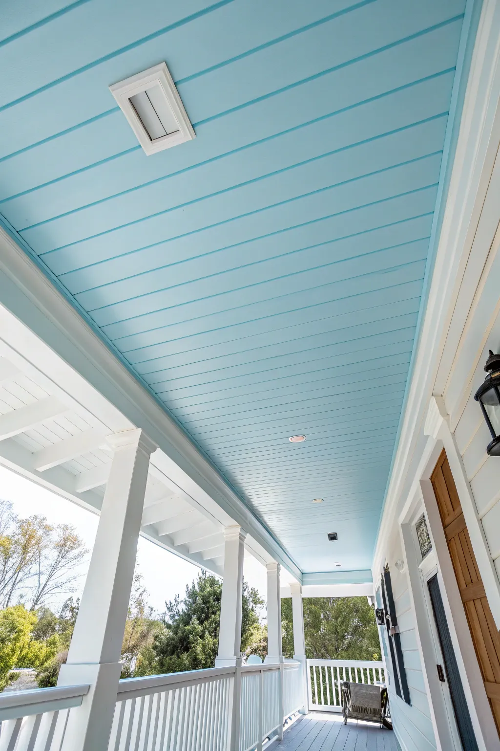 A sky-blue porch ceiling that feels like open air, with crisp white trim and soft boho warmth.