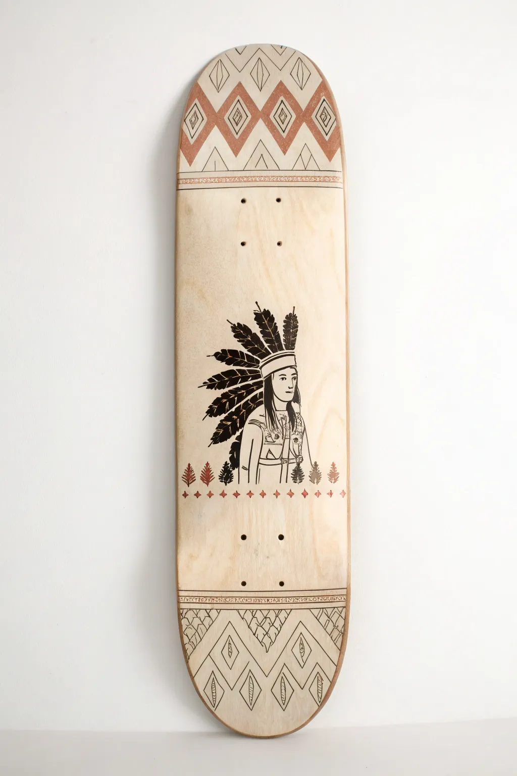 Minimalist boho skateboard deck: big central character framed by subtle repeating pattern