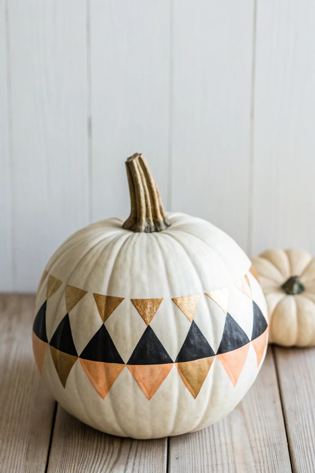 Crisp geometric color blocking on a white pumpkin in black and warm neutrals, minimalist style
