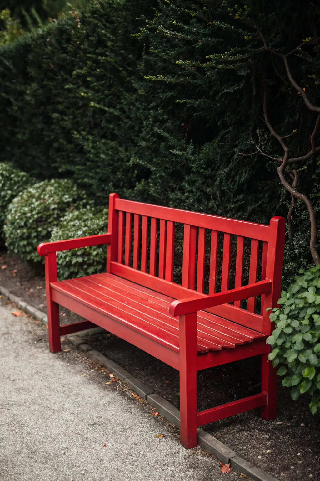 Bold red bench against lush green shrubs, a minimalist garden focal point for Scandinavian vibes.
