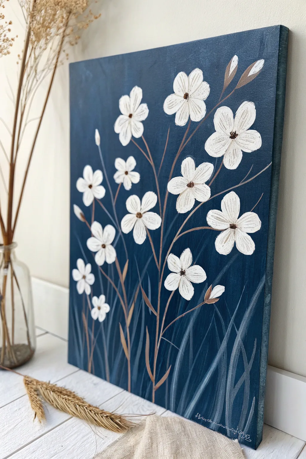 White blossoms pop against deep navy for a minimalist, boho-inspired blue background painting idea.