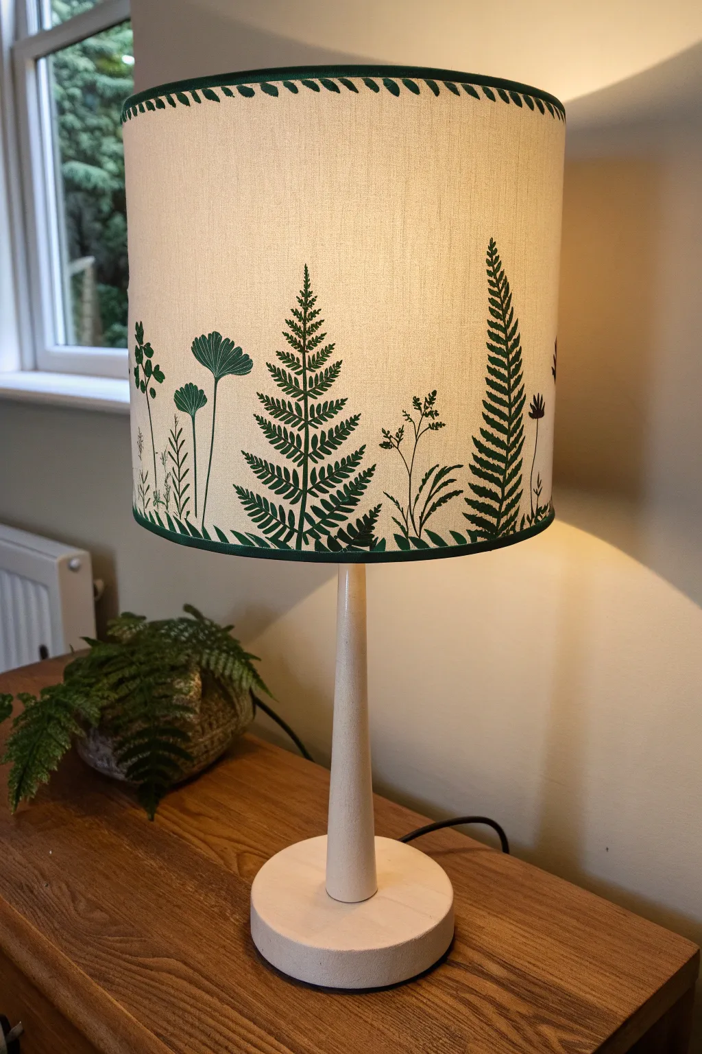 DIY lampshade with a crisp leafy silhouette border, glowing warm against clean minimalist decor