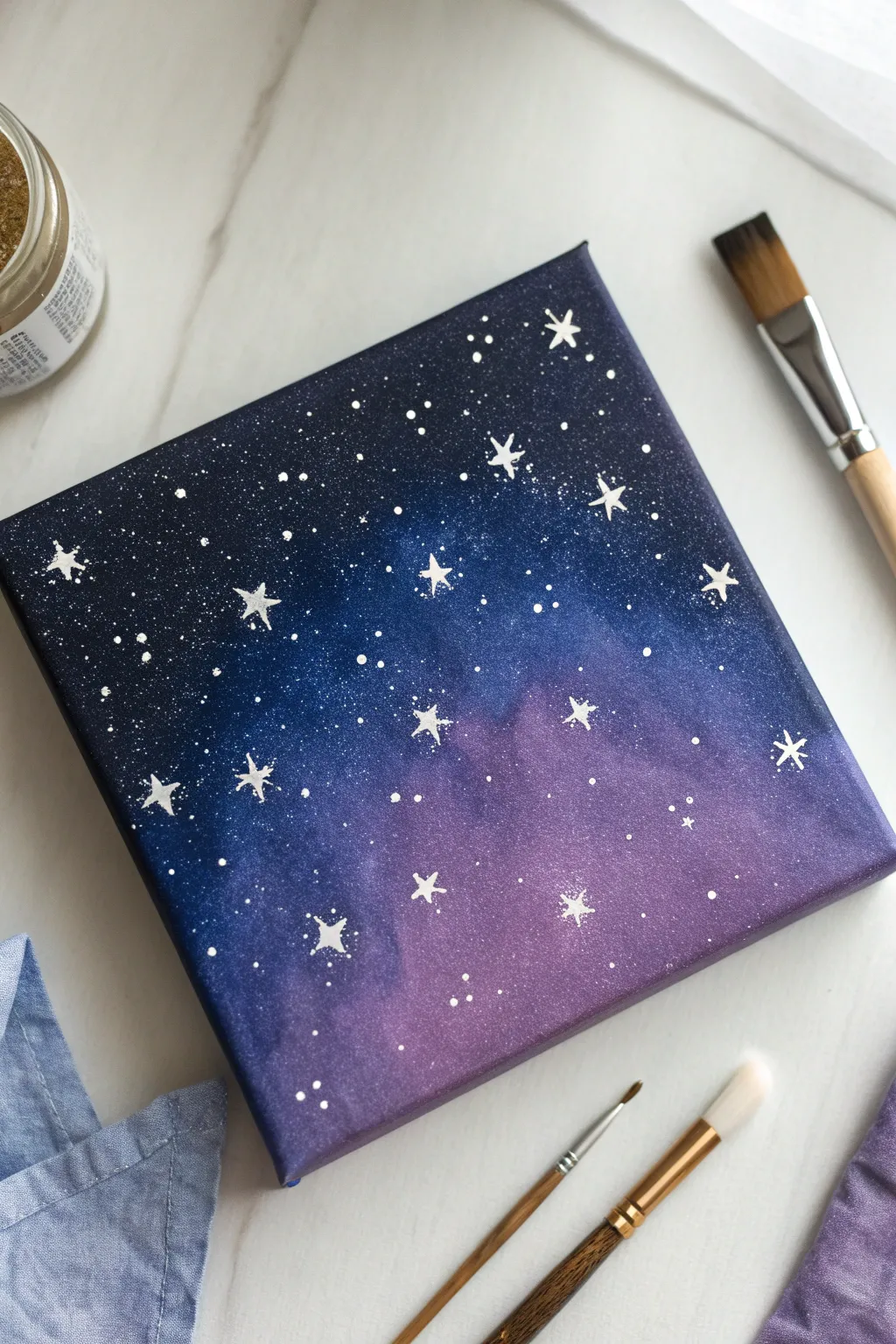 DIY galaxy night sky canvas with bold splatter stars and a clean, mess-friendly setup