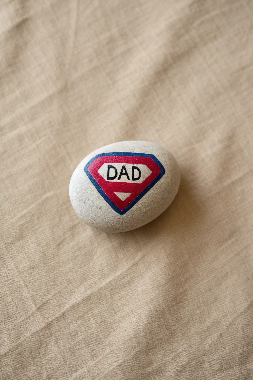 Paint a bold superhero emblem on a smooth rock for a simple Fathers Day gift that pops