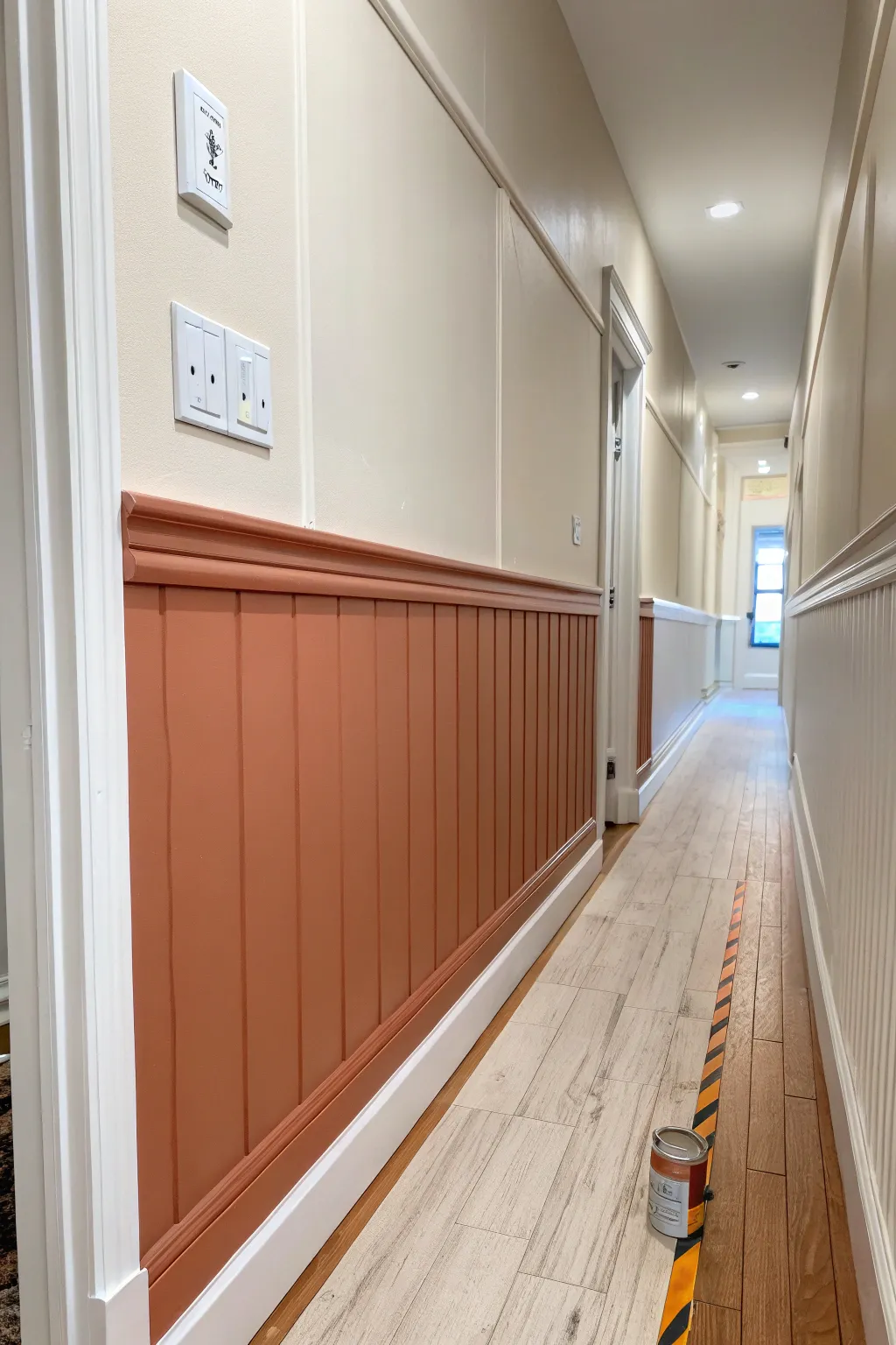 Half-painted walls that fake wainscoting on a budget, with a crisp tape line and bold warmth.