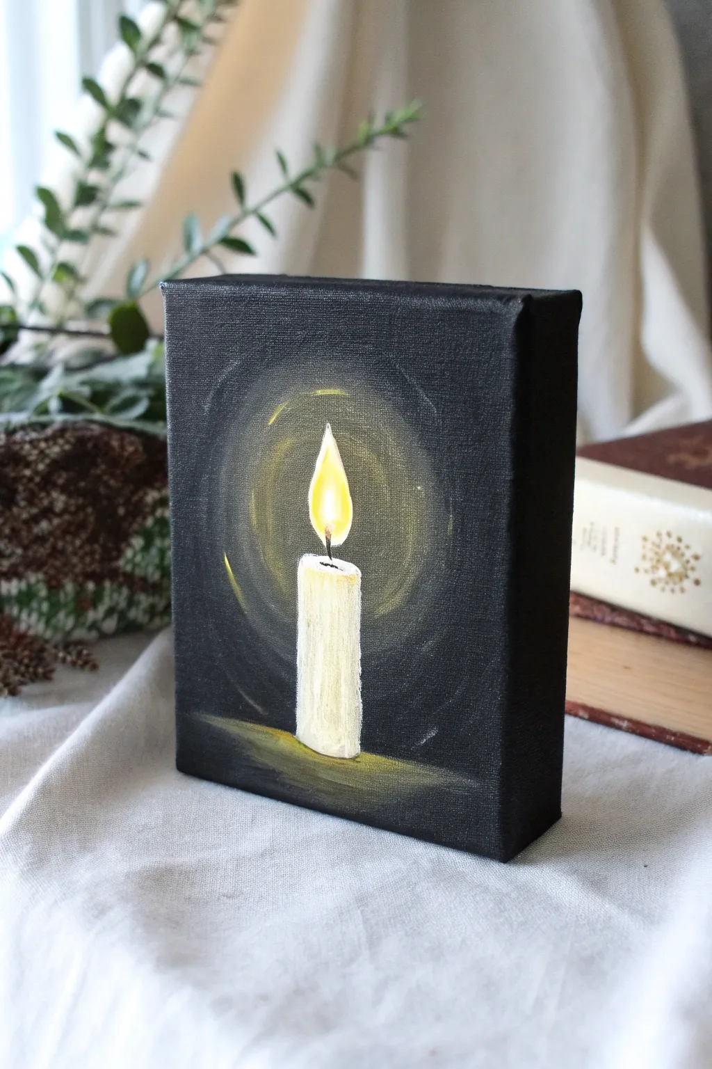 Mini black canvas candle with a warm glow halo, Scandinavian minimalism with a soft boho touch.