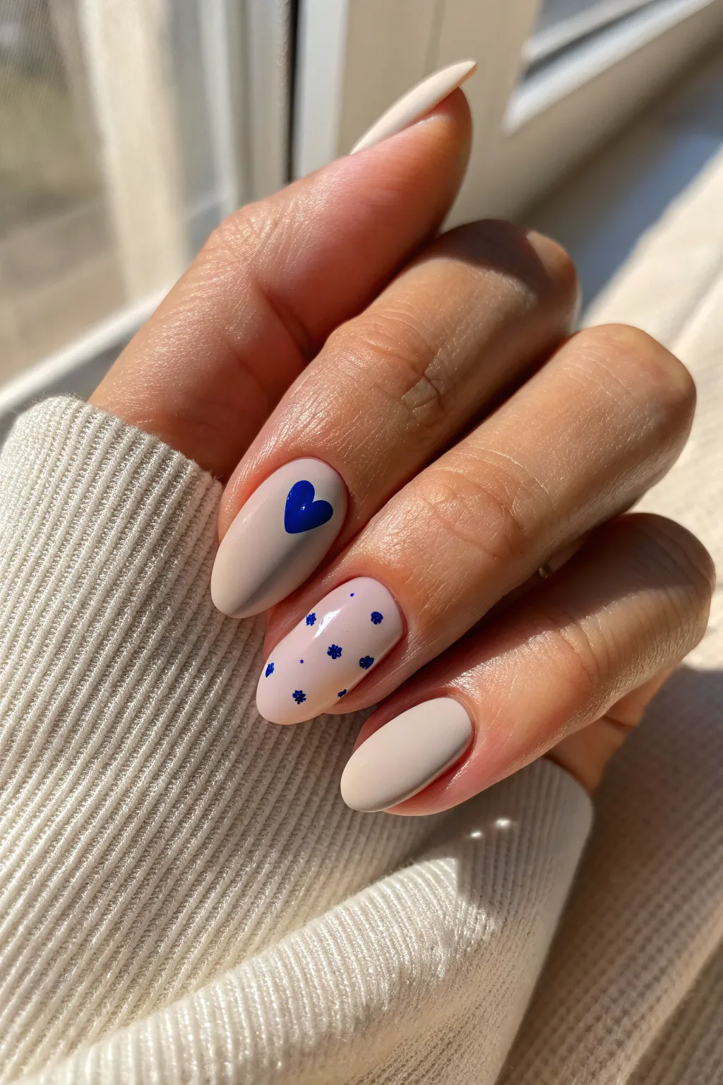 Neutral nude manicure with one tiny cobalt heart accent nail for minimalist boho charm.