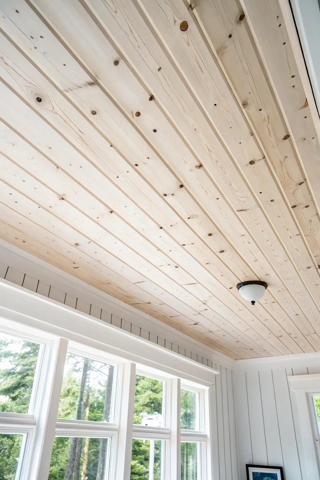 Soft white painted knotty pine ceiling that brightens the space while keeping its charm