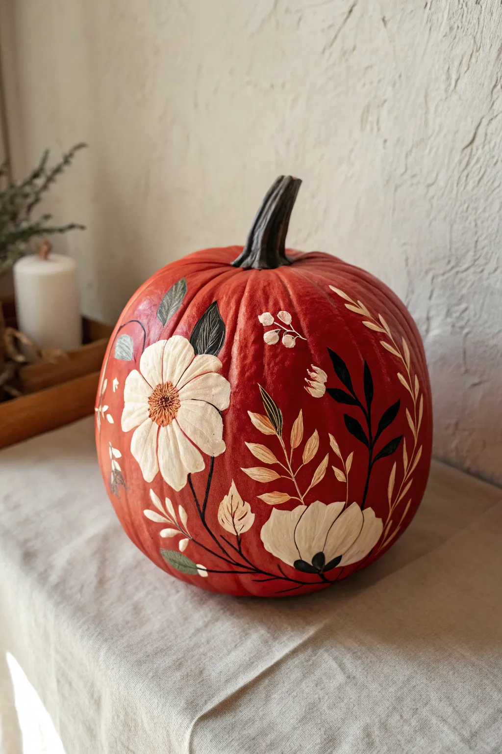 Hand-painted florals on a bold red pumpkin, cozy window light, minimalist boho charm.