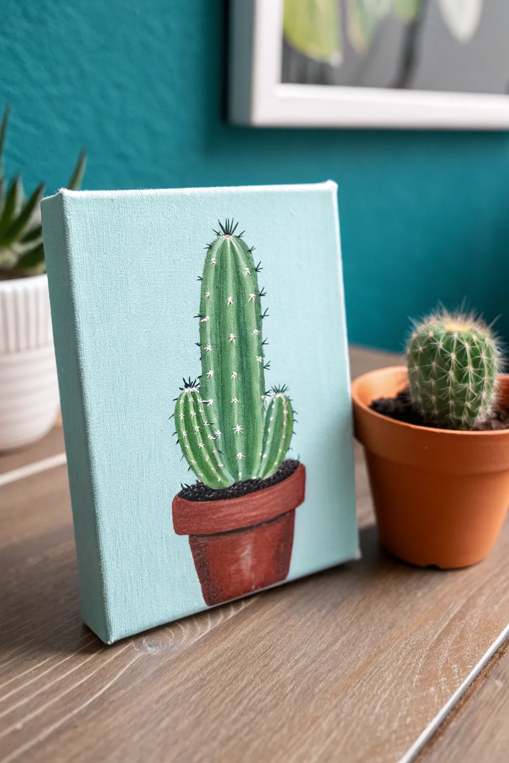 Minimal cactus canvas inspo with bold teal backdrop and terracotta pot, clean and cute.