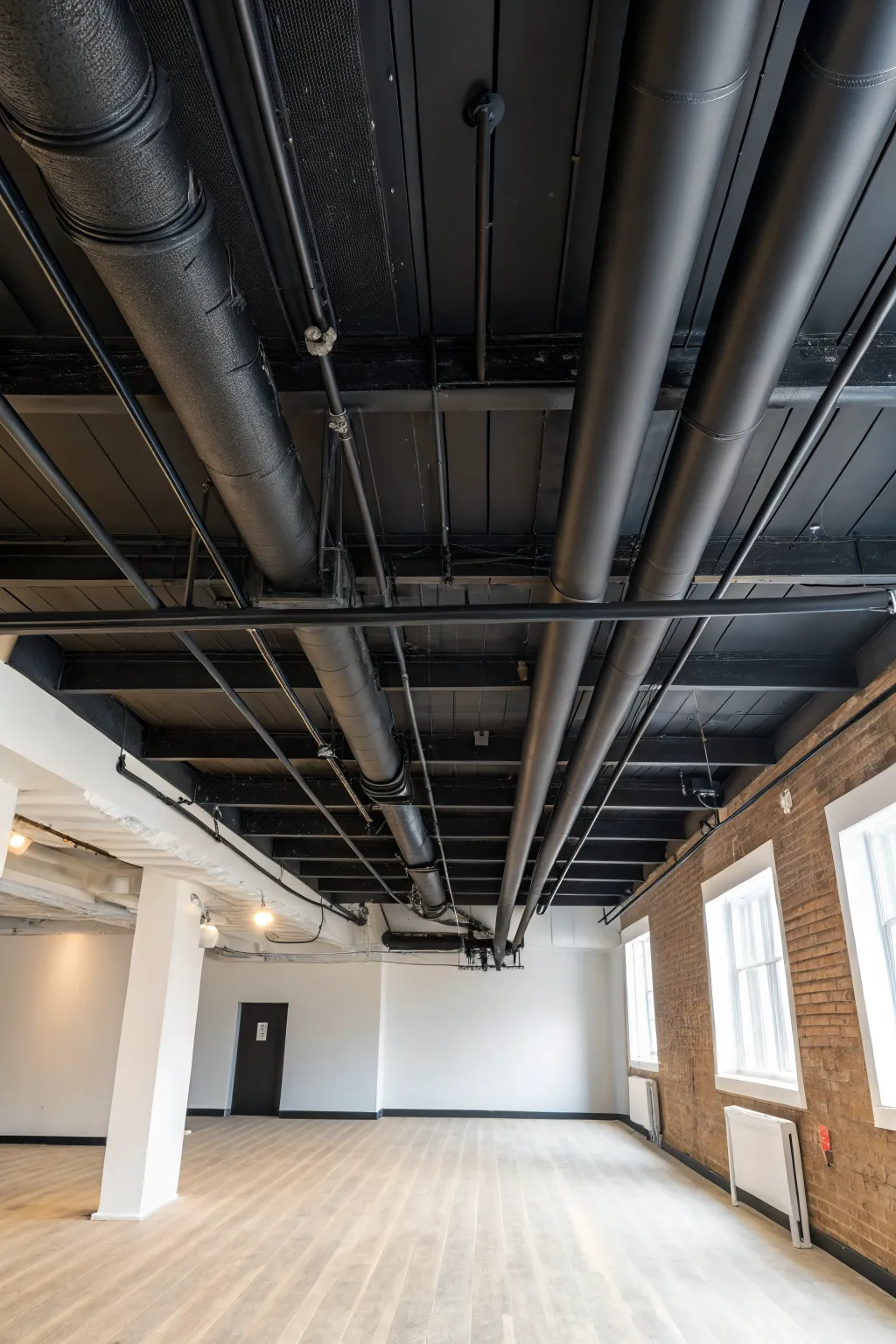 Flat black exposed ceiling makes a basement feel taller with a clean minimalist vibe