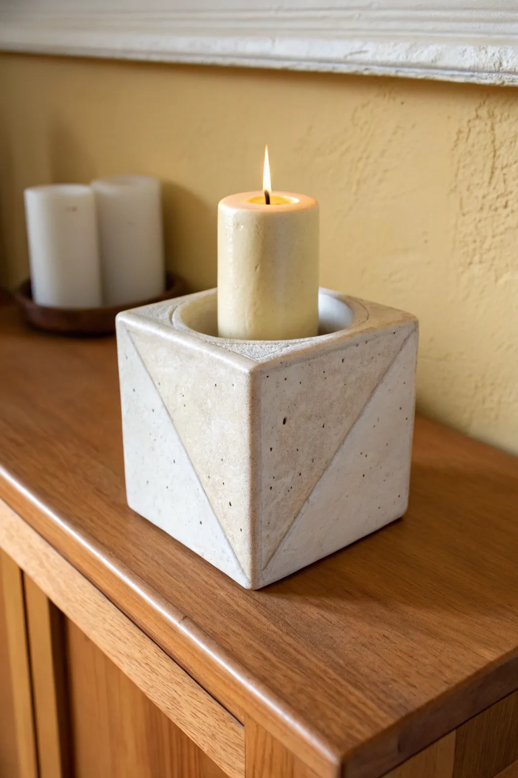 Minimal slab-built ceramic candle holder with a single taper, styled in warm neutral light