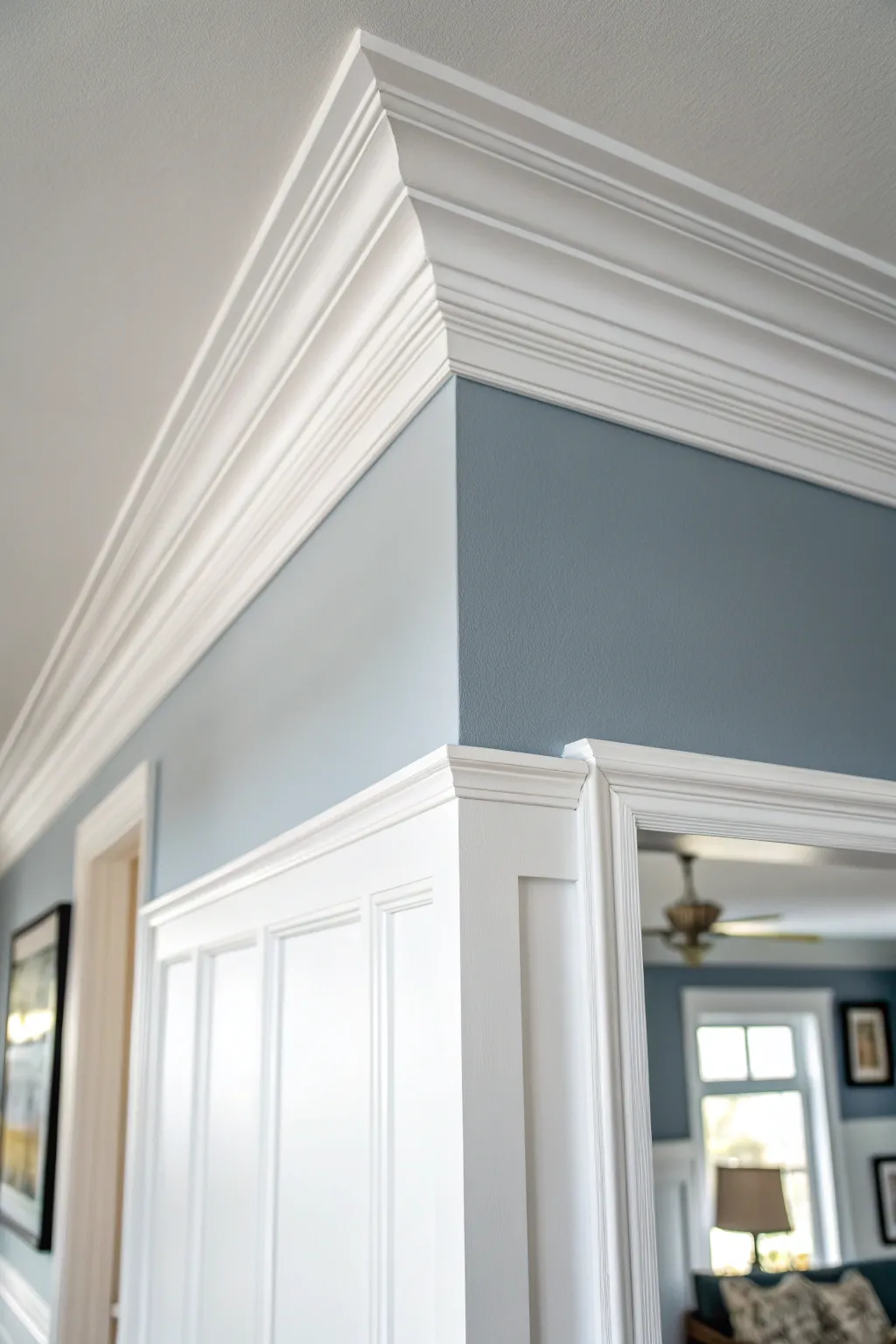 Cool white crown molding stands out against blue-gray walls with soft window light and clean contrast.