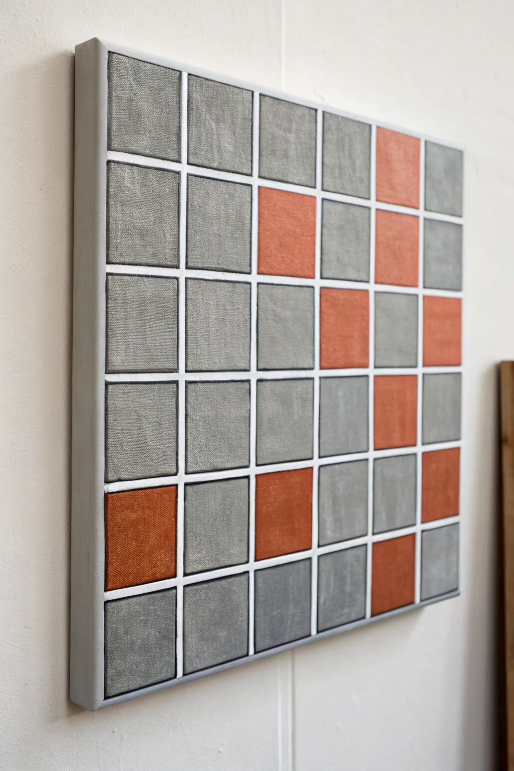 Monochrome grid painting with a few terracotta squares for a calm, modern focal pop.