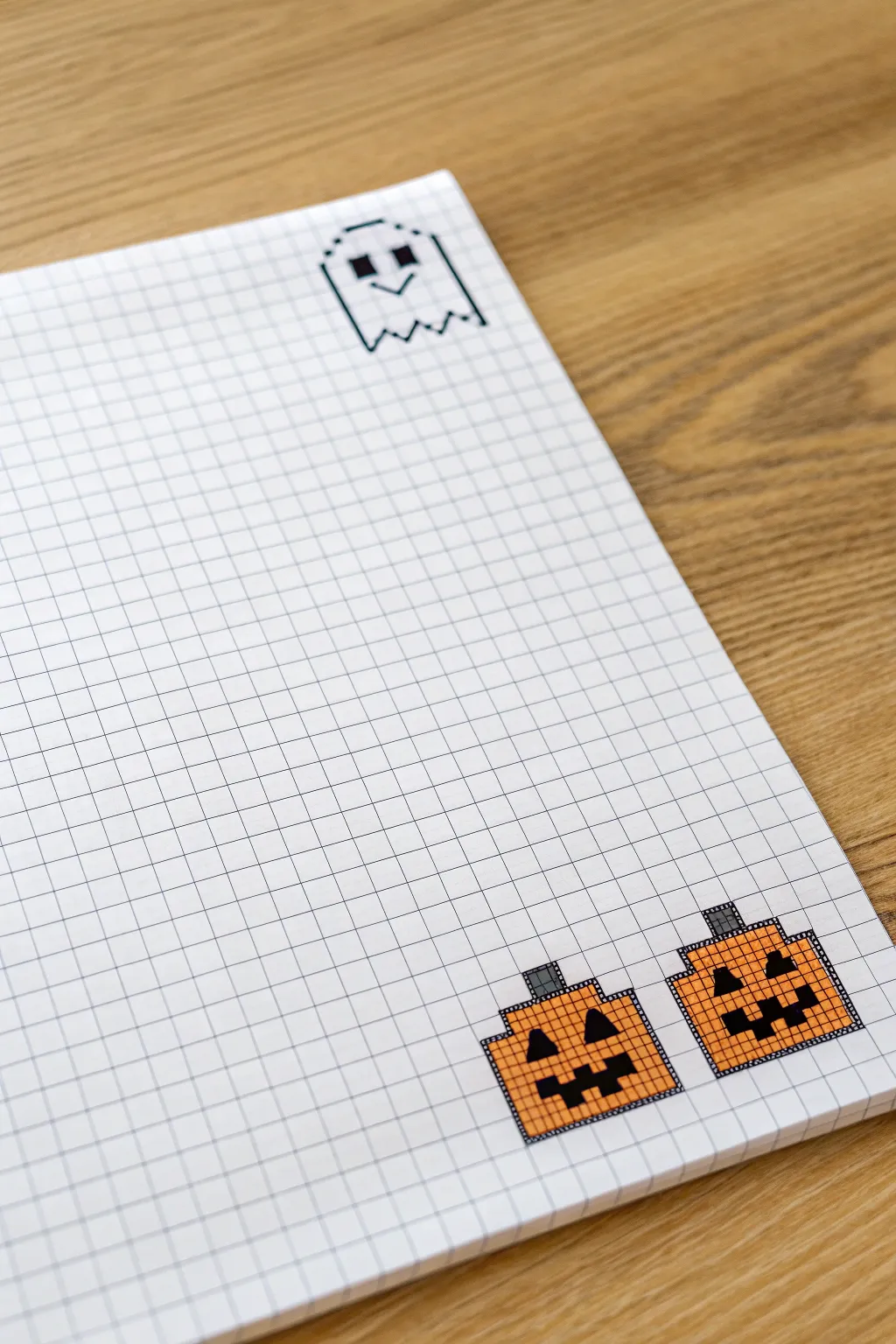 Cute ghost and jack-o-lantern duo on graph paper, a simple high-contrast grid pixel art idea.