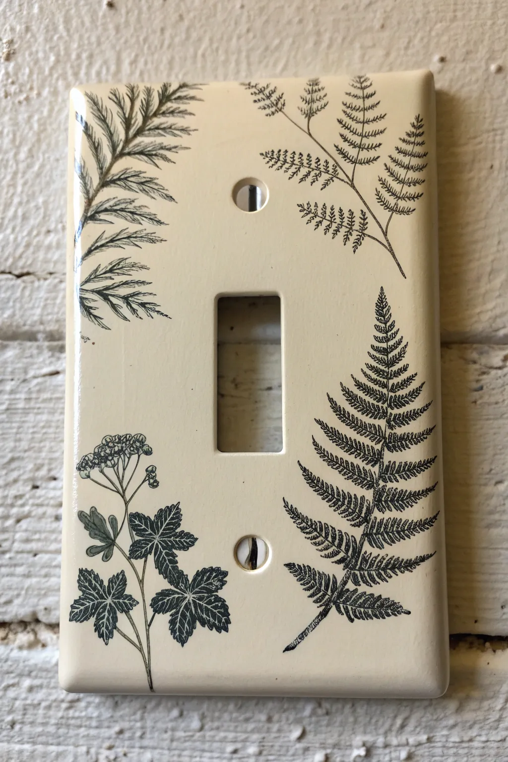 Two-tone botanical silhouettes turn a simple switch plate into calm, high-contrast wall art.