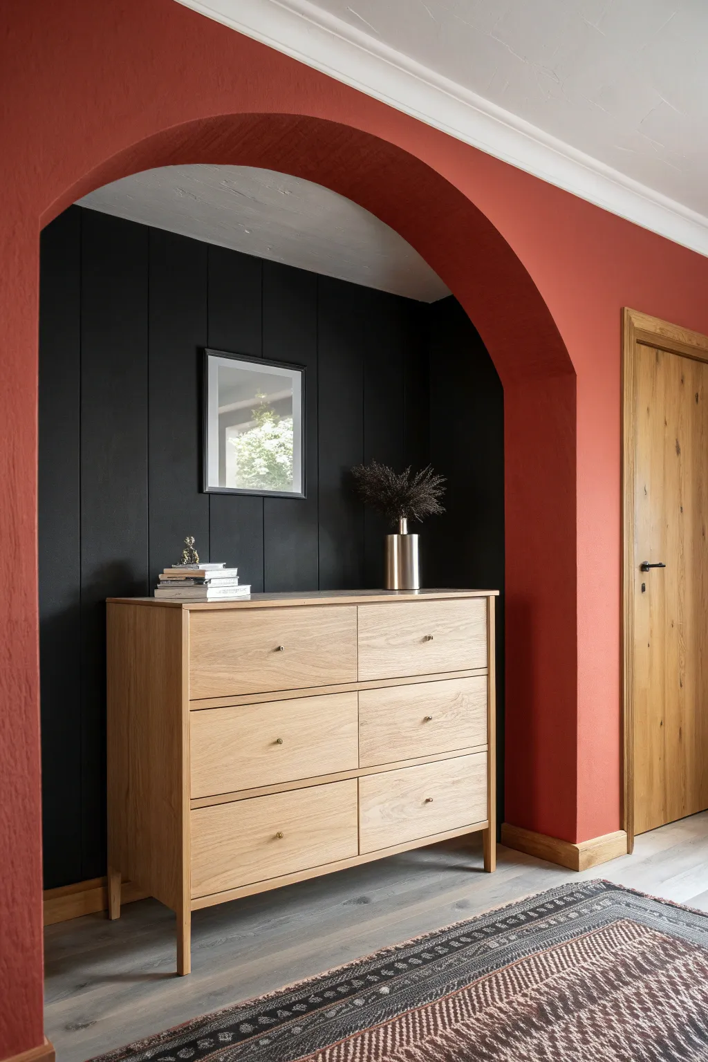 Deep red arch on matte black wall spotlights a minimalist oak dresser for bold, cozy contrast.