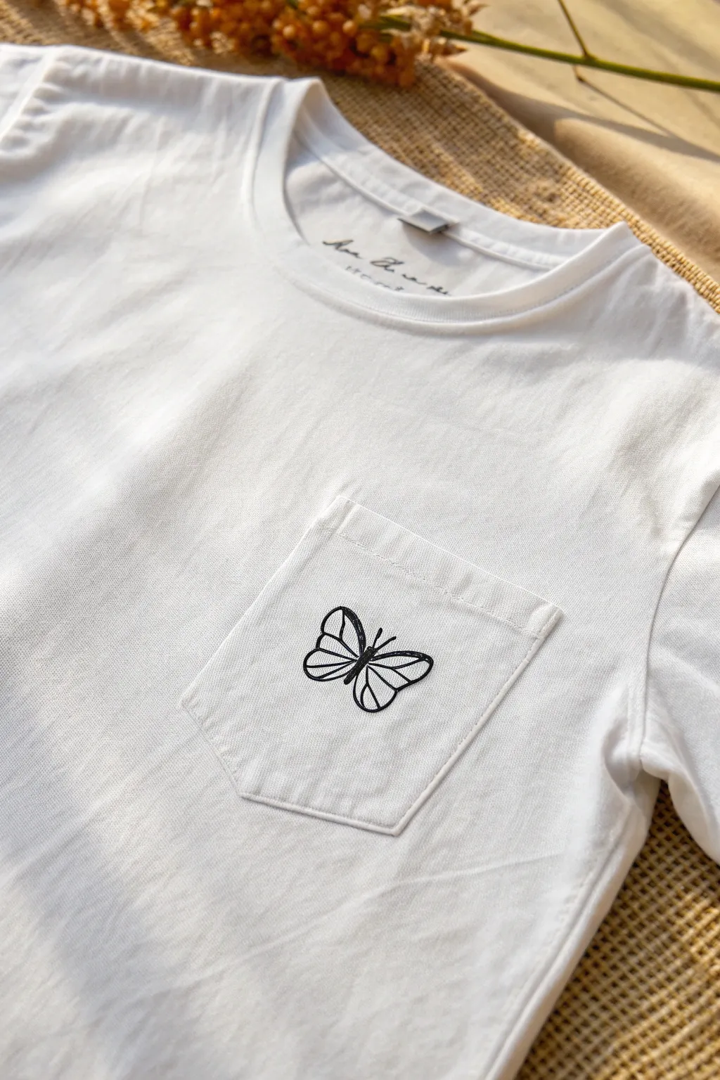 Simple butterfly outline by the pocket shows how easy t shirt drawings can look delicate